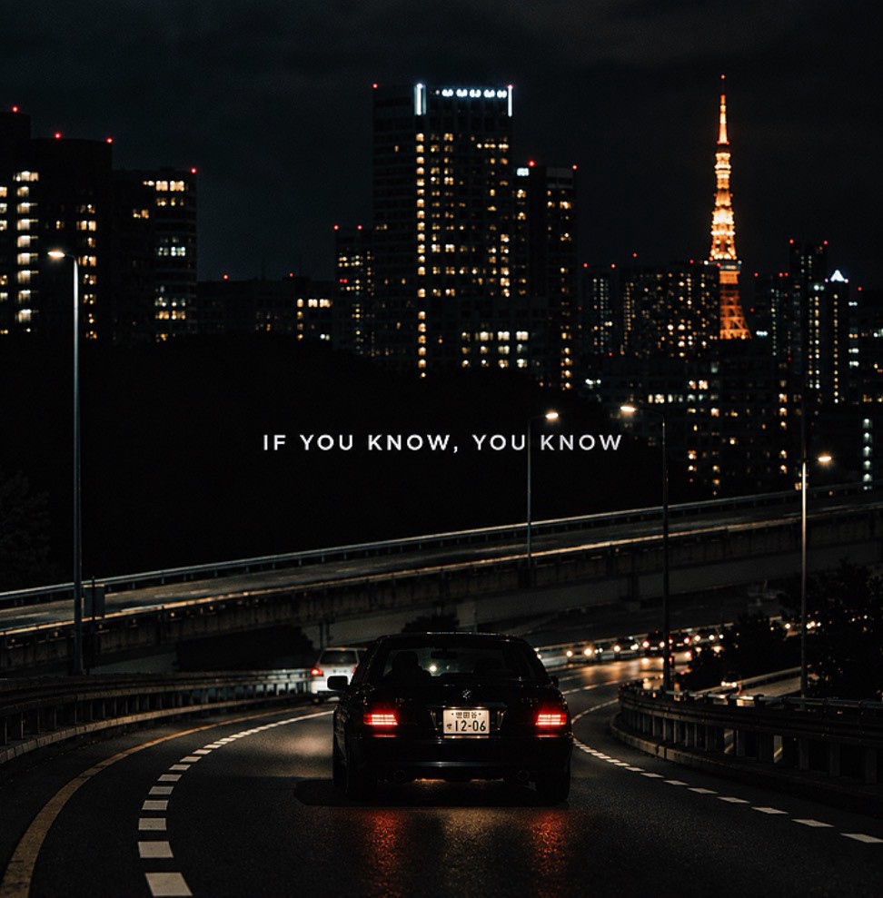東京タワーが灯る夜、都市の道路を走る黒い車